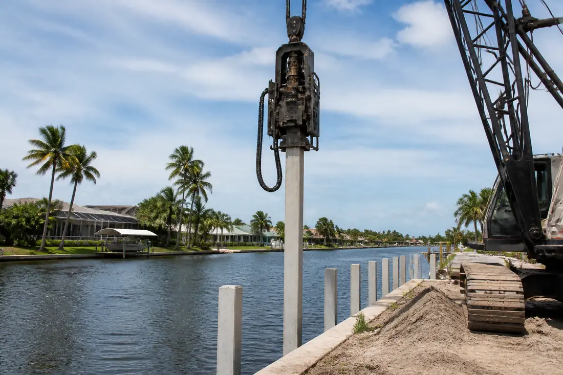 A pile being driven along the edge of a canal