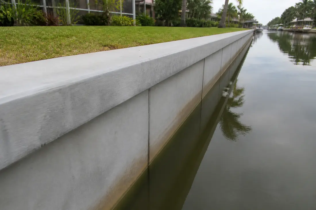 A concrete seawall and cap running along a residential canal in Charlotte County