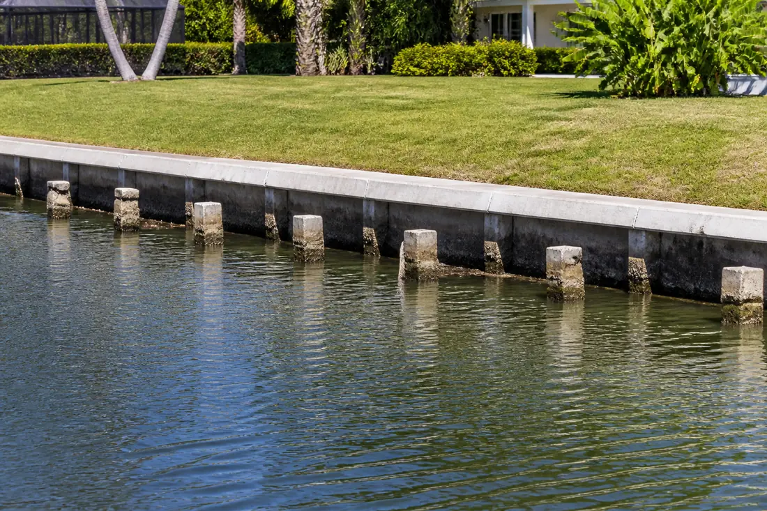 Cut-off concrete piling stubs standing in canal water where a dock has been removed