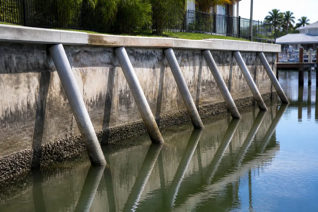 Angled batter piles driven against the face of a concrete seawall to brace it