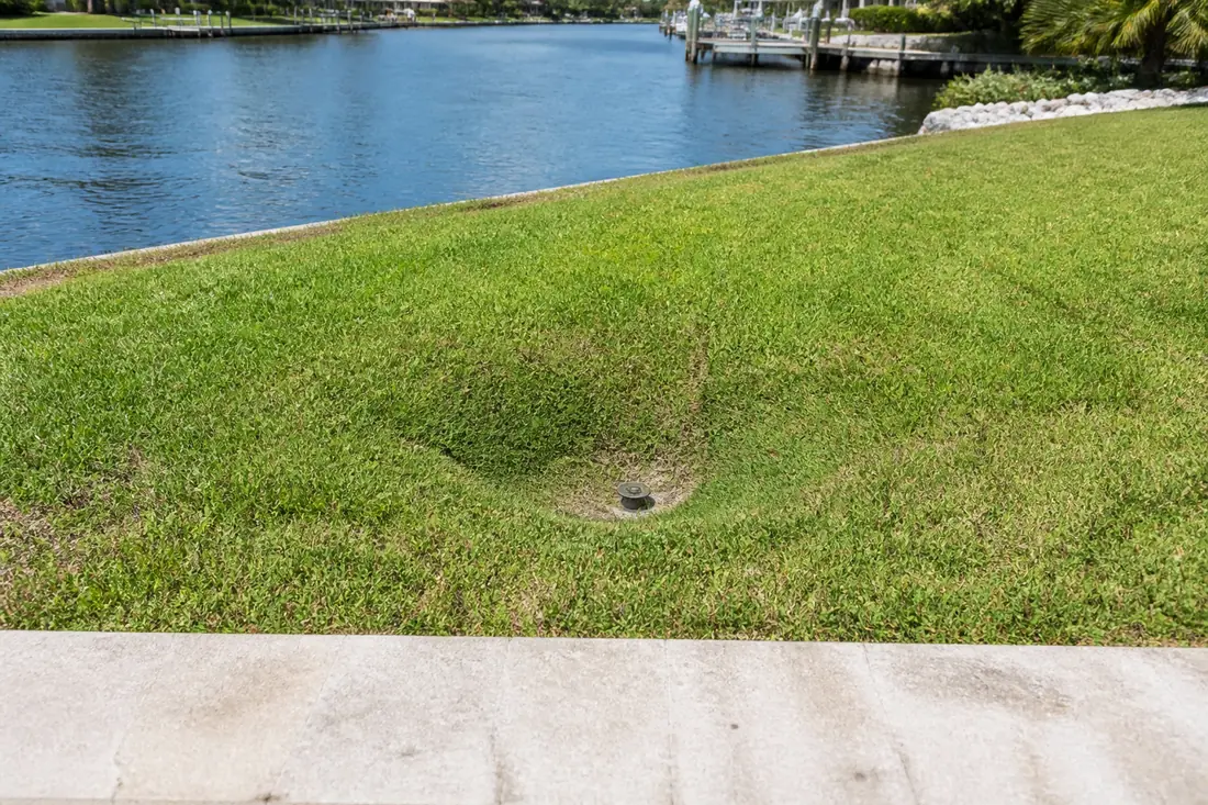 A shallow depression in a lawn a few feet back from a seawall cap